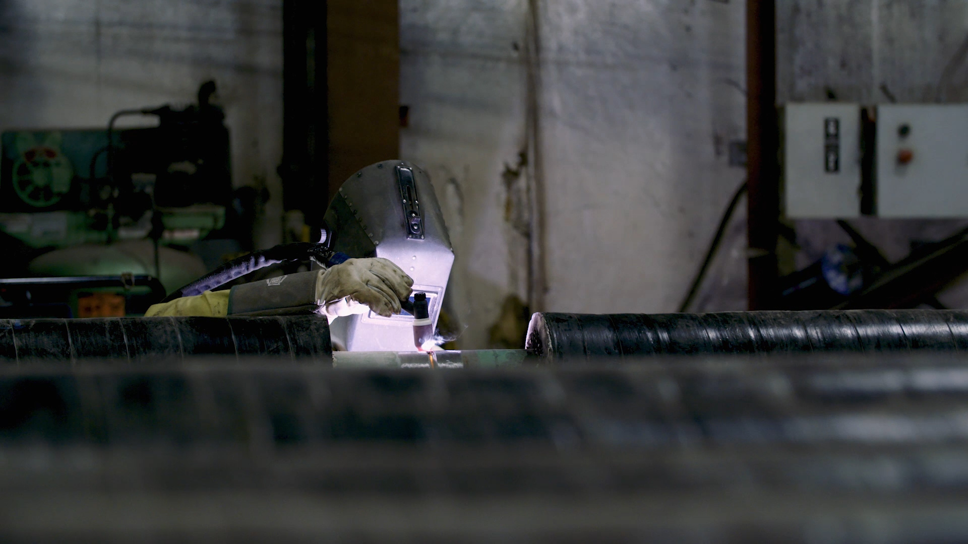 Pipefitter welding inside a pipe fabrication shop.